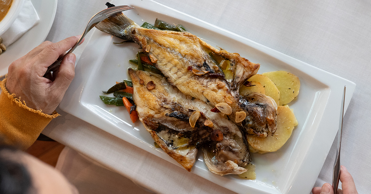 persona comiendo pescado local ibiza